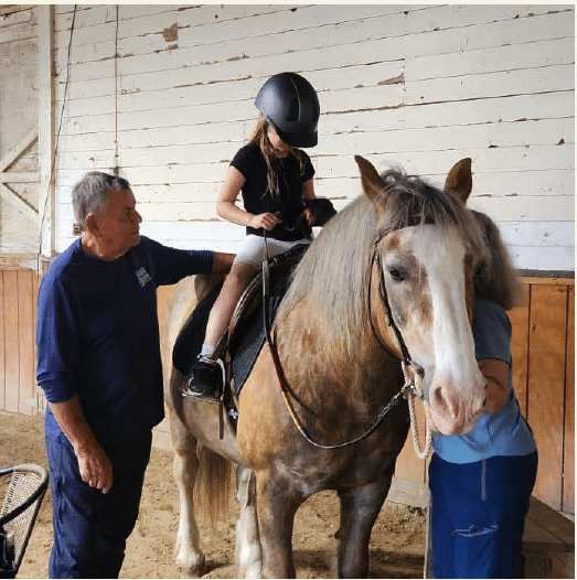 Child on horse with instructors next to them